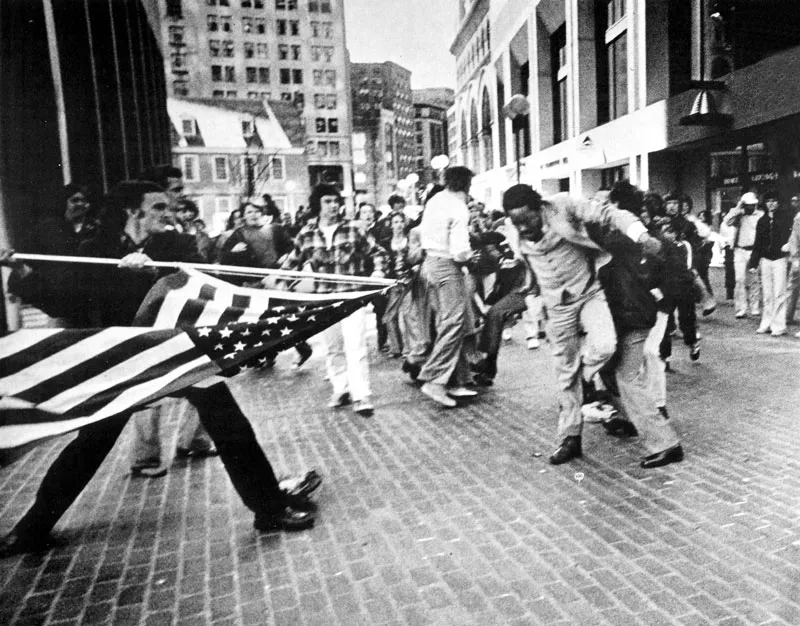 Cualquier arma se emplea en esta batalla entre negros y blancos frente al edificio de la Alcaldía de Boston.
(Stanley Formar; 1976).