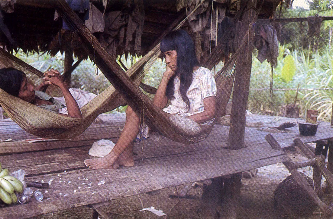 Mujeres Tikuna. Obsérvese la característica construcción de la vivienda unifamiliar sobre pilotes, en los grupos aculturados, y la plataforma de yaripa. Los chinchorros son hechos con fibras de cumare.
