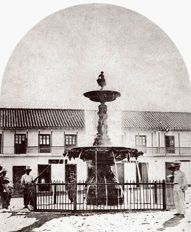 Plaza de Bolvar.  Casas de Juan de Dios Jaramillo y Alejandro Gutirrez.  La pila fue traida a lomo de Buey desde Honda por Manuel Tiberio y Tulio Estrada, a finales de siglo.  