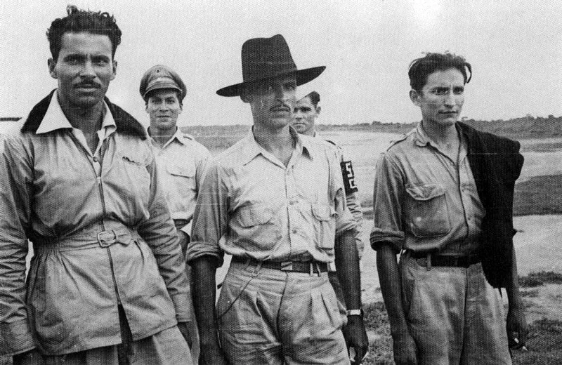 CARLOS CAICEDO. Guadalupe Salcedo (primero) y Dumar Aljure (segundo) acompañados de otro guerrillero y dos miembros del ejército. 1953. Copia reciente. Archivo Carlos Caicedo, Bogotá.