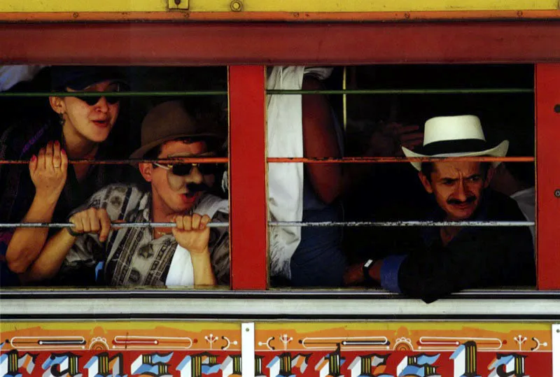 En “chiva” al carnaval del Diablo. Riosucio, Caldas. El bus de escalera, llamado así por sus bancas paralelas con puertas laterales, es propio del transporte entre ruralidades en Colombia y se ha caracterizado por el arte pictórico popular en sus paredes exteriores. Se le conoce como “Chiva” y se ha convertido en un símbolo de la Colombia campesina. Jeremy Horner