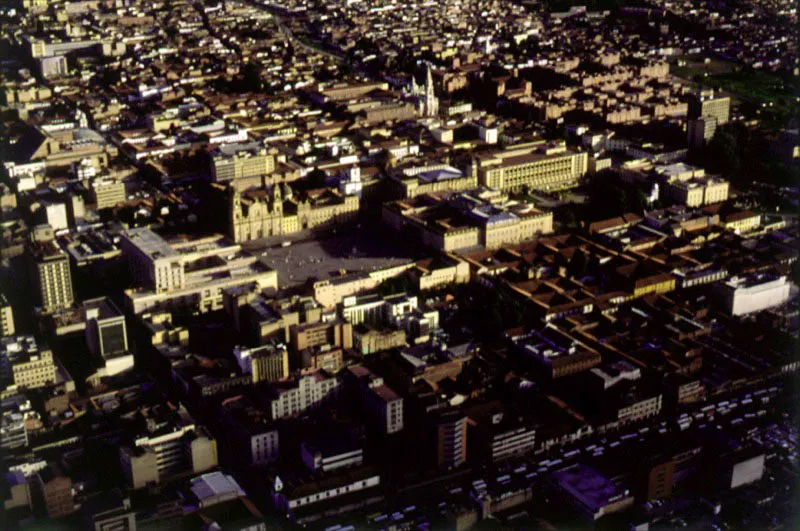 Panorámica del Centro Histórico y de la Plaza de Bolívar. El eje de la ciudad colonial era la Plaza Mayor, hoy Plaza de Bolívar. En ella se encontraban la Catedral, la Capilla del Sagrario, la Casa Consistorial y la Aduana, en el costado oriental, el Palacio de los Virreyes y la Real Audiencia en el costado sur, el nuevo Palacio de los Virreyes y la cárcel, conocida como Cárcel Chiquita en el costado occidental, y los almacenes principales estaban en el costado norte. El primer barrio fue el de La Catedral, a su alrededor surgieron los de San Jorge, El Príncipe, Del Palacio, Las Cruces, Santa Bárbara. A finales del siglo XVI la ciudad comenzó a extenderse al norte del río San Francisco, hoy Avenida Jiménez de Quesada. Pilar Gómez