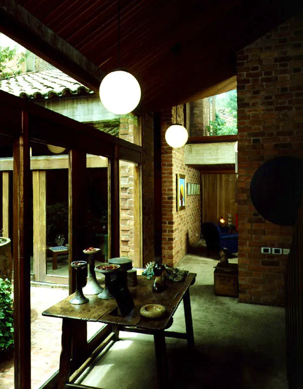 El pequeño patio interior da lugar a toda la arquitectura de la casa. Todo converge hacia allí. La pendiente de las cubiertas, al tiempo que señala la importancia del patio, se levanta hacia aperturas que crean vistas con los jardines inmediatos o con los cerros lejanos. La uniformidad cromática de los materiales de muros, pisos y techo, convierte una mancha de color en todo un evento. / Bogotá, D.C. Arquitecto, Jacques Mosseri.