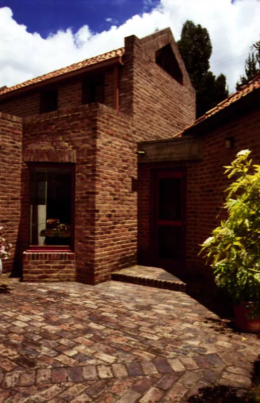 Las formas de la casa son precisas y dentro de ellas los espacios se subdividen de manera sutil. Verticalmente, se distinguen tres ámbitos: el del amoblamiento a nivel del piso; el más alto, el de la cubierta con su estructura de madera; y entre éstos un tercer ámbito virtual, un vacío cuyo papel es el de dar la escala definitiva. Los muros muestran un trabajo bastante elaborado tanto en sus contornos como en las hendiduras que forman cavidades de diverso tipo y función. El espacio interior está contenido en un volumen cuya definición es igualmente precisa. / Chía, Cundinamarca. Arquitectos, Jorge Rueda, Carlos Morales.