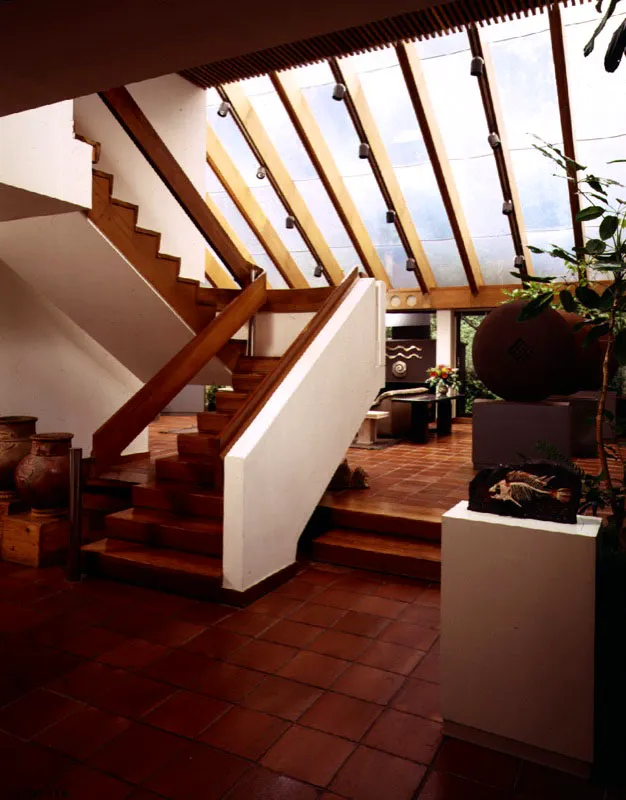 La marquesina, uno de los aportes relativamente recientes al diseño interior de la casa, se trabaja como parte importante de su espacialidad. Las líneas formadas por sus apoyos tienen eco en las líneas de las maderas del cielo raso. El efecto del volumen flotante se repite en el tratamiento de la escalera. / Bogotá, D.C. Arquitecto, Luis Kopec.