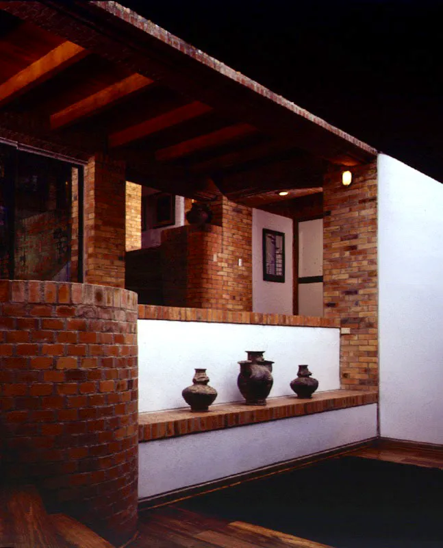 La fragmentación de la casa, que obedece no sólo a asuntos topográficos sino a una concepción arquitectónica, se hace evidente tanto en las direcciones de los espacios, acentuadas por las direcciones de las bóvedas, como en la multiplicidad de ángulos visuales que se captan desde un punto. Esa fragmentación hace que la experiencia de la casa reúna sensaciones diversas al estar en un recinto o al recorrerla. Las superficies blancas, enmarcadas por bordes en ladrillo, se destacan como planos contrastantes en la textura del espacio interior. / Tenjo, Cundinamarca. Arquitectos, Willem Goebertus, Catalina Mariño.