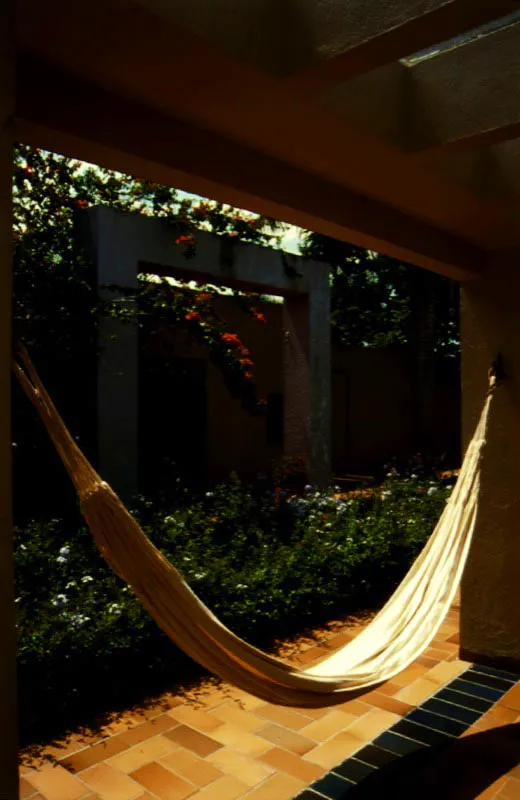 El corredor separado de la casa es un pretexto para elaborar juegos geométricos con los soportes verticales y los elementos horizontales de la pérgola y del diseño de pisos. También es un pretexto para romper esa geometría con la curva natural de una hamaca. / Anapoima, Cundinamarca. Arquitecta, Mónica Gómez de Espinosa.