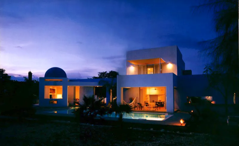 Al atardecer las aberturas de la casa se muestran como grandes bocas destinadas a tomar aire y frescura y llevarlos a los espacios interiores. Los volúmenes se destacan nítidamente contra el cielo, en una silueta imposible de captar en otro momento. / Ricaurte, Cundinamarca. Arquitecto, Jorge Pérez Norzagaray.