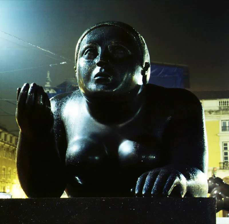 Mujer recostada con fruto.  
1996.  
Bronce, edicin de 3.  
143 x 118 x 363 cm.  
Plaza del Comercio, Lisboa. 1998 