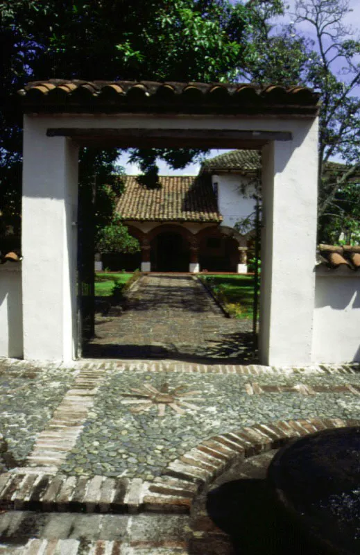 Casa de Guacarí,
Valle del Cauca.
En rigor, no es actualmente una construcción rural,
ni lo que hoy existe corresponde a la primera sede de la hacienda de este nombre. Es posible que algunos de los componentes arquitectónicos de la casa original hayan sido incorporados a lo actual, construida cuando el caserío de Guacarí creció en torno a la hacienda fundada en el siglo XVII, y se hizo necesario levantar una iglesia propia del lugar. Al comenzar el siglo XIX la edificación pasó a ser casa cural. Los espacios libres circundantes, singulares en un núcleo urbano, son propios de una casa
de finca o hacienda.
Si el volumen realzado del piso alto es característico de las casas rurales de la región, la reciente restauración de la casa dejó al desnudo los atípicos arcos rebajados en ladrillo de las galerías del piso bajo, en un equívoco acento decorativo.
