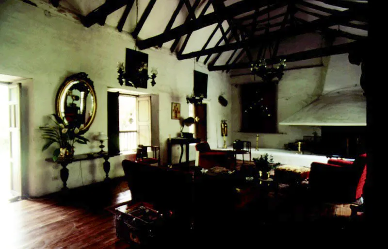 Baza, Valle de Tenza, Boyacá.
Una casa que “deja existir” el campo en torno suyo, a la manera de las alquerías árabes andaluzas. Nótese, abajo a la izquierda, la variante usual en Boyacá de la armadura de cubiertas en “par y nudillo” técnicamente primitiva, realizada usando maderas rollizas excesivamente delgadas a modo de pares. Estas, muy flexibles pero livianas
y baratas, se curvan bajo el peso del
tejado, y requieren riostra o jabalcones (más rollizas) apoyados en los tirantes, para sostenerlas. Tan confuso sistema artesanal refleja lo pintoresco de la ignorancia técnica
y lo divertido de
la improvisación.
A la derecha, el
acceso al patio es
un indudable acierto arquitectónico, reflejo del arte de saber entrar a los lugares.