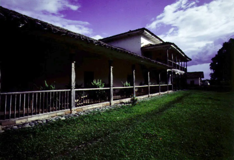 La Concepción de Amaime. El Cerrito, Valle del Cauca.
Es la casa de hacienda arquitectónicamente más singular y destacada de la región. Llega a su forma “final” en la segunda mitad del siglo XVIII. Se destaca su volumetría en un
lugar llano, topográficamente indiferente, por lo que depende de su propia arquitectura para cualificar los espacios en torno suyo. Posee además de la casa de los señores, de planta compacta, una capilla exenta, una ramada (vivienda de peones y depósitos), y tuvo también el tradicional baño al aire libre y un extenso acueducto del cual quedan algunos rastros. A cierta distancia de la casa subsiste el trapiche azucarero. La localización de la capilla y el volumen sobreelevado del extremo occidental de la casa, provisto de un balcón alto y galería baja con columnas talladas, conforman un conjunto arquitectónico de espléndida calidad.