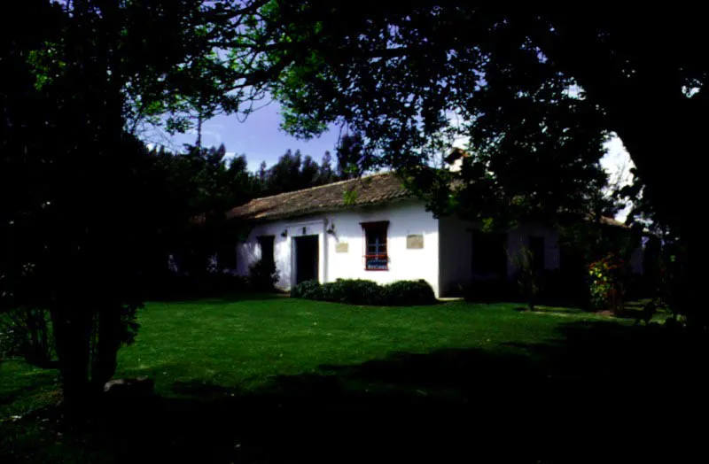 Gotua, Iza, Boyacá.
Surgió posiblemente en la segunda mitad del siglo XVIII o los comienzos del XIX, cuando sobrevino la subdivisión de las grandes encomiendas coloniales que abarcaban los valles de Sogamoso, Firavitoba, Iza y Pesca. Es la típica casa baja boyacense organizada en dos, tres o (a veces) cuatro costados de un patio central. Se puede
decir que esta es arquitectura rural minimalista, vale
decir, que no se
puede lograr más
con menos recursos. Al igual que otros congéneres suyos
en la región, pasó
por un proceso de época republicana en el cual le fueron aplicados cielos rasos muy bajos y se reformaron vanos
de puertas y ventanas, dotando a éstas de
rejas de hierro “arrodilladas”, propias de casas urbanas del siglo XIX. El énfasis ambiental de Gotua es casi totalmente hacia el patio interior, cuyas proporciones y carácter marcan el tono evocativo y gracioso de la casa. Cada patio interior boyacense posee rasgos distintivos individuales, aunque prácticamente todos pertenezcan al mismo principio ordenatorio espacial.