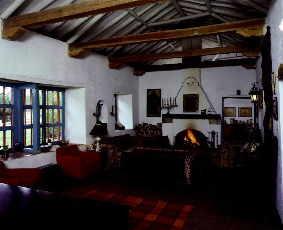 Gotua, Iza, Boyacá.
Surgió posiblemente en la segunda mitad del siglo XVIII o los comienzos del XIX, cuando sobrevino la subdivisión de las grandes encomiendas coloniales que abarcaban los valles de Sogamoso, Firavitoba, Iza y Pesca. Es la típica casa baja boyacense organizada en dos, tres o (a veces) cuatro costados de un patio central. Se puede
decir que esta es arquitectura rural minimalista, vale
decir, que no se
puede lograr más
con menos recursos. Al igual que otros congéneres suyos
en la región, pasó
por un proceso de época republicana en el cual le fueron aplicados cielos rasos muy bajos y se reformaron vanos
de puertas y ventanas, dotando a éstas de
rejas de hierro “arrodilladas”, propias de casas urbanas del siglo XIX. El énfasis ambiental de Gotua es casi totalmente hacia el patio interior, cuyas proporciones y carácter marcan el tono evocativo y gracioso de la casa. Cada patio interior boyacense posee rasgos distintivos individuales, aunque prácticamente todos pertenezcan al mismo principio ordenatorio espacial.
