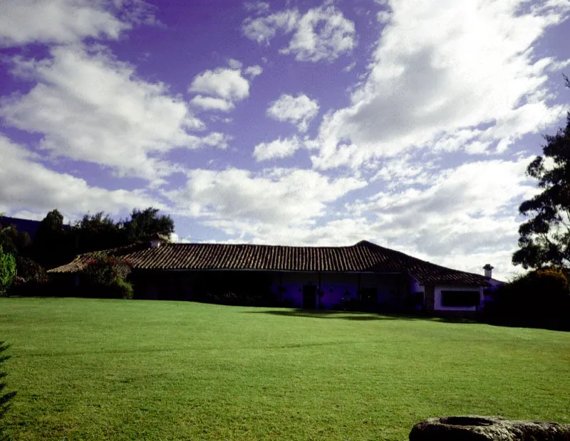 Chaleche, alrededores de Sesquilé, Cundinamarca.
Existen tres casas rurales que llevan o han llevado el mismo nombre. La casa de hacienda de época colonial tardía, ilustrada aquí, y
dos interesantes
casas de finca de
época republicana construidas entre el final del siglo XIX
y el comienzo del
XX, producto de la subdivisión de tierras de la hacienda colonial, resultado
a su vez del fraccionamiento
de la vasta encomienda de Sesquilé al comienzo del siglo XVIII. La casa de época colonial tuvo
un evidente crecimiento por etapas hasta bien entrado el siglo XIX, sin bruscos cambios de volumetría tales como los pisos altos añadidos a las casas de hacienda vallecaucanas, lo que explica la suave relación entre el paisaje y la forma actual de la casa.