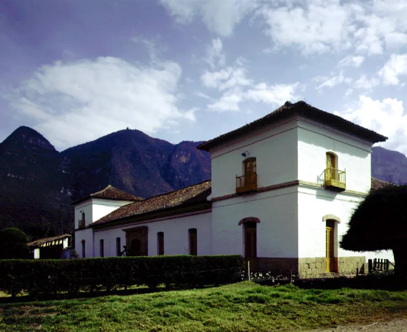 Aposentos, Simijaca, Cundinamarca. La casa combina un certero sentido intuitivo de lugar, aparente en su localización en una concavidad de los cerros circundantes, con la elegancia simétrica de su volumetría y fachada principal, lo cual tiene un evidente origen académico. El resultado es la casa
de hacienda más atípica, pero arquitectónicamente más interesante del período colonial en la Nueva Granada, así fuese construida al final de aquél.
Los muros delimitantes de los potreros vecinos a la casa prolongan el dominio espacial de ésta sobre el paraje donde se sitúa.