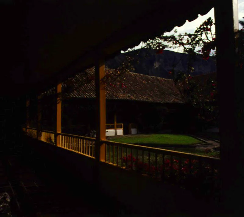Aposentos, Simijaca, Boyacá.
Las generosas proporciones del
patio principal de Aposentos, reflejan su origen teórico.
Nótese el contraste que ofrece este patio con el de la casa de Gotua, Iza, Boyacá. Ambos obedecen al mismo concepto de ordenación espacial
y fueron construidos con idénticos materiales y métodos constructivos, pero los resultados ambientales son muy distantes entre sí. Uno se hizo simplemente para vivir, el otro para contemplar su elegancia formal.
La inevitable intervención de
época republicana
en la casa (cielos rasos planos, enchapado
y molduración de columnas en madera, colocación de barandas sobre los poyos hacia
el patio, etc.) afectó marginalmente la calidad ambiental de los espacios. Nótese cómo la presencia dominante de los tejados artesanales parece pertenecer a
un mundo conceptual muy diferente de la ortodoxia modular
de las columnatas en torno al patio o la ordenación de la fachada principal
de la casa, como
si ésta hubiese sido pensada para ser cubierta con terrazas planas, a la manera de la provincia valenciana de donde era oriundo el autor de la casa, Fray Domingo de Petrés.