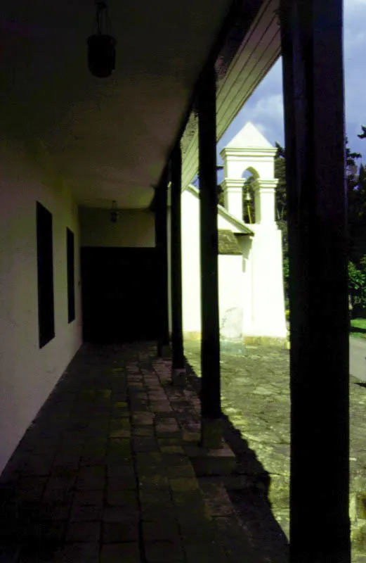 Yerbabuena, La Caro, Chía, Cundinamarca. Parece ser que los tramos originales
de la casa de Yerbabuena, formando una “L”
en dos costados del patio interior,
fueron edificados al final del siglo XVIII, cuando la dehesa de Hatogrande fue desmembrada y surgieron varias haciendas a raíz de tal subdivisión. Ya en la primera mitad del siglo XIX la casa fue sucesivamente
ampliada y reformada hasta adquirir una extensión insólita entre sus congéneres sabaneros. En la segunda mitad
del siglo XIX la republicanización de Yerbabuena le dio el tono arquitectónico que hoy, redecorado considerablemente varias veces, es visible en el tramo más “moderno” de la casa, (arriba) incluyendo cerramientos de galerías en vidrieras
“a la francesa” y rejas pseudo-sevillanas de hierro. Los aleros “de caja” usuales en las casas de hacienda caucanas, pero insólitos en plena Sabana de Bogotá y visibles aquí en las fachadas y hacia el patio interior, le fueron impuestos a la casa al final de la década de los cuarenta.