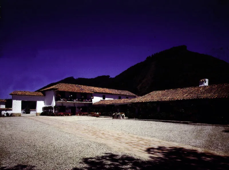Fagua, Cajicá, Cundinamarca.
Posee una volumetría y una organización espacial irregulares con respecto a los patrones de organización espacial usuales en las haciendas de la sabana de Bogotá. Combina uno y dos pisos en torno a varios pisos abiertos sucesivos, lo cual es indicio de un largo y complejo crecimiento por etapas, del paso de la casa por las manos –y las reformas– de múltiples propietarios y de no pocas intenciones arquitectónicas truncas. Esto le otorga informalidad y sabor a la casa. A partir de las últimas décadas del siglo XVI se levantó, en las tierras que más tarde se agruparían bajo el nombre de Fagua, lo que debió ser un rancho temporal. Los primeros tramos “en firme” de la casa original parecen datar del primer tercio del siglo XVII, y la forma y extensión actual de la casa es alcanzada durante la primera mitad del siglo XVIII. Pese a los períodos de abandono por los que ha pasado, la conservación formal y ambiental de la casa es notable, destacándose el excepcional mantenimiento de las portadas y muros circundantes.