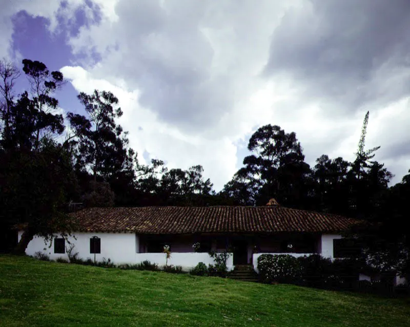 Fusca, Torca, Cundinamarca.
Si la casa de Fagua es una organización espacial irregular, a la cual se llegó luego de abigarrados episodios constructivos, Fusca, en cambio, ostenta la ortodoxia espacial propia de una arquitectura levantada de un golpe, con una intención única. Fusca data de 1778 a 1780
–lo cual la hace comparativamente tardía– y fue pensada ajustándola con precisión al declive del terreno, y luego con cierto rigor en torno
a un patio central, aunque también con una amplia galería a modo de salón abierto a la vista de la sabana adyacente. Esta última no contradice el patio central. Por el contrario, lo hace parte de una lógica y bella secuencia para el recorrido de la casa llegando a ésta por
atrás, y no por el frente, contorneando el patio, atravesando los salones principales y saliendo por último a la galería-balcón del frente.