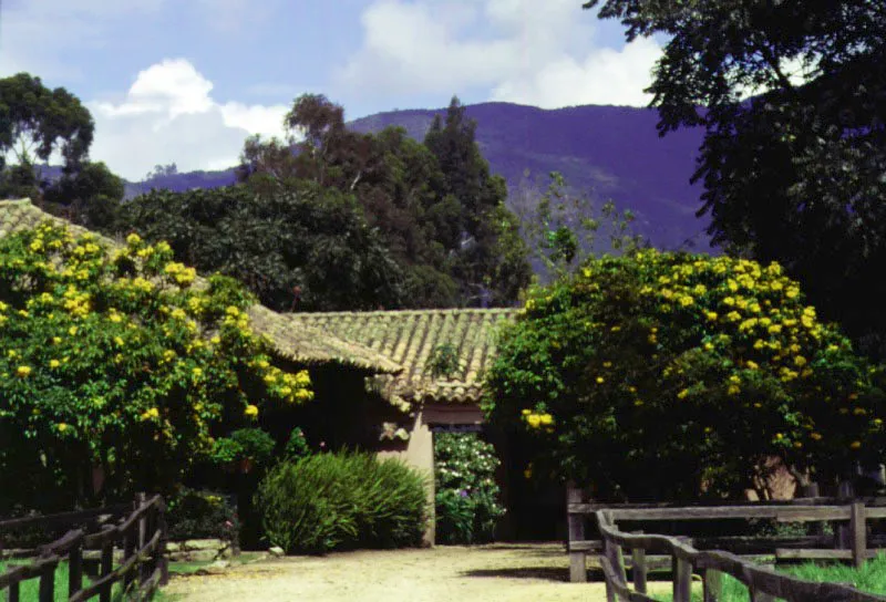 La Esmeralda, Tabio, Cundinamarca.
Forma parte de las
edificaciones rurales creadas al final de la época colonial, cuando se intensificó la desmembración de los latifundios en la sabana de Bogotá. La enorme propiedad de El Novillero, se dividió en algún momento de su historia en once fracciones, una de
las cuales llegó
a ser La Esmeralda. Aunque el tamaño y época de construcción puedan variar mucho de una casa de hacienda a otra, la gracia de los tejados o la delicada relación entre casa y lugar son constantes en todas. En La Esmeralda el prisma imaginario de espacio en el cual se inscribe la casa es casi tangible, y la casa misma podría ser tan natural como sus árboles.