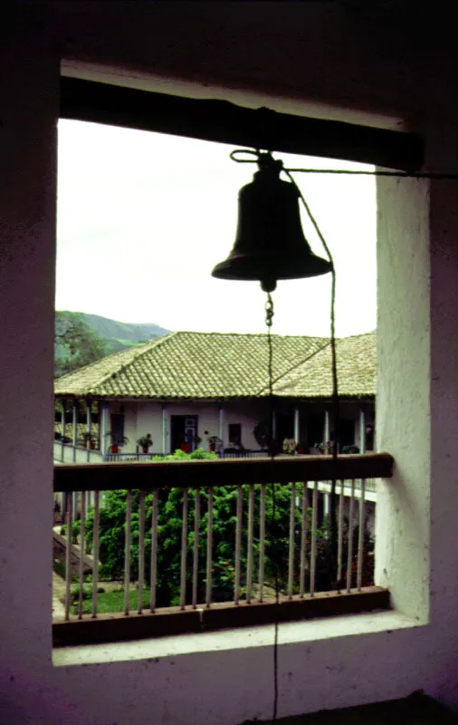 Bomboná, Nariño.
Se sitúa en una región montañosa donde las haciendas fueron escasas pero notablemente extensas. Pocos latifundios del sur del país llegaron a tener casas de cierta importancia arquitectónica y aun menos de ellas sobrevivieron hasta el siglo actual. De ahí el carácter excepcional de Bomboná. Para su construcción debió ser necesario recorrer infinidad de veces las leguas que separan su localización del punto más próximo donde era posible obtener teja de arcilla, buen adobe y ante todo, buena cal. Y devastar, de paso, una enorme área de bosques para sacar de ellos las gruesas columnas, dinteles y soleras que conforman la recia estructura de cubiertas y galerías de la casa.
Al ver una casa de hacienda en un paraje remoto, se tiende a olvidar el esfuerzo físico y tecnológico que su construcción supone y que califica decisivamente su arquitectura.
Izquierda, El mirador atípico que rompe la unidad volumétrica de los tejados. Se requiere muy poco para alterar la continuidad y la armonía formal de los tejados coloniales. Esta atalaya, indispensable para la vigilancia de la comarca circundante en una región de larga y difícil historia de contiendas militares y azarosa existencia cotidiana, es una adición de la primera mitad del siglo XIX, no un rasgo original de la edificación colonial de mediados del siglo XVIII.