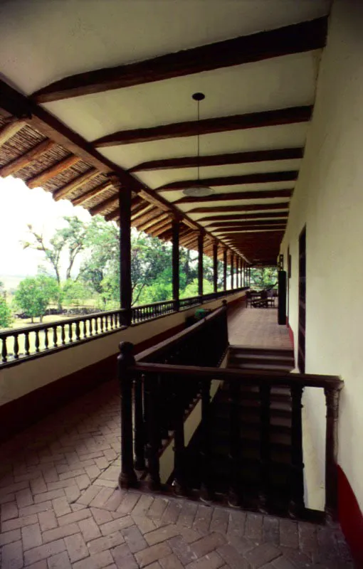 Calibío. Popayán, Cauca.
Las grandes galerías del piso alto de Calibío son prácticamente idénticas a las que se podrían hallar aún hoy en campos y ciudades desde La Mancha hasta Córdoba, en tierras hispánicas, pero fueron creadas de esa manera y no otra porque el paisaje caucano así lo exigía ante la memoria y la intuición de sus constructores. Por ello son, como el resto
de la casa, inseparables del lugar que ésta ocupa. La casa de hacienda es un escenario para una modalidad existencial cotidiana que no podría ni quiso ser jamás la misma, a un lado y otro del Mar Océano. En Casa Colonial se dijo: “Las casas neogranadinas mostrarán una… mezcla de rasgos, mitad castellanos, mitad andaluces, es decir, algo que no
se había dado ni
en Castilla ni en Andalucía. Se conformó así el
matiz original…
del florecimiento,
en el nuevo continente, de un género arquitectónico tan antiguo como la humanidad misma.
En éste fue siempre clara su estirpe, pero evidente también su íntima relación con la tierra donde fue levantado”.
