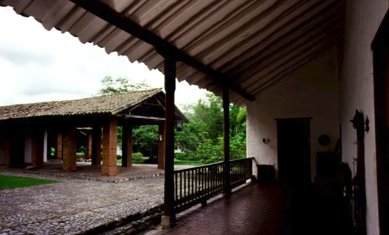 Piedechinche, El Cerrito, Valle del Cauca.
En la mayoría de los trapiches “antiguos”
del Valle del Cauca se observan versiones propias de la tecnología industrial del siglo XIX o XX en las estructuras destinadas a usos utilitarios. En Piedechinche el trapiche retiene su carácter de época colonial, con reformas del siglo XIX. Los hornos y chimenea datan de la misma época, pero la bagacera y las ramadas son más antiguas, como es también el acueducto, parcialmente elevado sobre arcos de ladrillo.
Al contrario de lo que ocurrió en las haciendas de olivar, de Andalucía, donde la casa señorial estaba integrada a la industria adyacente, los trapiches de caña del Valle del Cauca dan la sensación de estar por casualidad en las proximidades de las casas de hacienda propiamente dichas. La arquitectura industrial de la época colonial hizo uso de estructuras desprovistas de toda concesión a la gracia posible de las formas construidas, creando así un marcado contraste ambiental y plástico con las casas de hacienda adyacentes. Un trapiche se podía colocar en cualquier parte donde hubiera agua, pero una casa de hacienda requiere un lugar en especial.