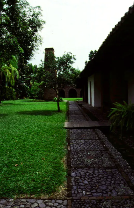 Piedechinche, El Cerrito, Valle del Cauca.
En la mayoría de los trapiches “antiguos”
del Valle del Cauca se observan versiones propias de la tecnología industrial del siglo XIX o XX en las estructuras destinadas a usos utilitarios. En Piedechinche el trapiche retiene su carácter de época colonial, con reformas del siglo XIX. Los hornos y chimenea datan de la misma época, pero la bagacera y las ramadas son más antiguas, como es también el acueducto, parcialmente elevado sobre arcos de ladrillo.
Al contrario de lo que ocurrió en las haciendas de olivar, de Andalucía, donde la casa señorial estaba integrada a la industria adyacente, los trapiches de caña del Valle del Cauca dan la sensación de estar por casualidad en las proximidades de las casas de hacienda propiamente dichas. La arquitectura industrial de la época colonial hizo uso de estructuras desprovistas de toda concesión a la gracia posible de las formas construidas, creando así un marcado contraste ambiental y plástico con las casas de hacienda adyacentes. Un trapiche se podía colocar en cualquier parte donde hubiera agua, pero una casa de hacienda requiere un lugar en especial.