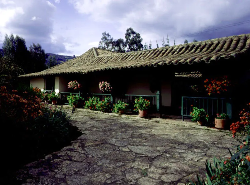 Altamira, Tenjo, Cundinamarca.
Es un buen ejemplo de la dimensión ambiental y significados adicionales que una casa de hacienda adquiere al paso del tiempo, cuando su carácter utilitario cede el lugar a otras razones para su conservación. Altamira parece ser uno de los muchos nombres dados en el siglo XIX a propiedades y casas surgidas a raíz de la desmembración de las haciendas más antiguas en la sabana de Bogotá y alrededores.
En una casa de dimensiones tan modestas como ésta, resulta aparente que para los constructores de época colonial el tamaño físico de las construcciones no tenga importancia conceptual. El acierto formal y ambiental que casi invariablemente lograban podía ser a formato mínimo o enorme, sin que por ello debieran variar los materiales y técnicas constructivas. En la arquitectura minimalista de Altamira los tejados no pueden ser más expresivos (ni más bajos), ni su patio más reducido o más evocador.