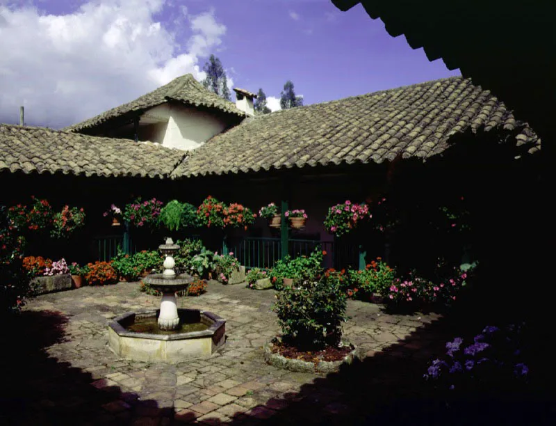 Altamira, Tenjo, Cundinamarca.
Es un buen ejemplo de la dimensión ambiental y significados adicionales que una casa de hacienda adquiere al paso del tiempo, cuando su carácter utilitario cede el lugar a otras razones para su conservación. Altamira parece ser uno de los muchos nombres dados en el siglo XIX a propiedades y casas surgidas a raíz de la desmembración de las haciendas más antiguas en la sabana de Bogotá y alrededores.
En una casa de dimensiones tan modestas como ésta, resulta aparente que para los constructores de época colonial el tamaño físico de las construcciones no tenga importancia conceptual. El acierto formal y ambiental que casi invariablemente lograban podía ser a formato mínimo o enorme, sin que por ello debieran variar los materiales y técnicas constructivas. En la arquitectura minimalista de Altamira los tejados no pueden ser más expresivos (ni más bajos), ni su patio más reducido o más evocador.