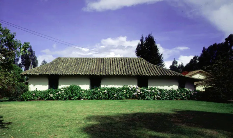Altamira, Tenjo, Cundinamarca.
Es un buen ejemplo de la dimensión ambiental y significados adicionales que una casa de hacienda adquiere al paso del tiempo, cuando su carácter utilitario cede el lugar a otras razones para su conservación. Altamira parece ser uno de los muchos nombres dados en el siglo XIX a propiedades y casas surgidas a raíz de la desmembración de las haciendas más antiguas en la sabana de Bogotá y alrededores.
En una casa de dimensiones tan modestas como ésta, resulta aparente que para los constructores de época colonial el tamaño físico de las construcciones no tenga importancia conceptual. El acierto formal y ambiental que casi invariablemente lograban podía ser a formato mínimo o enorme, sin que por ello debieran variar los materiales y técnicas constructivas. En la arquitectura minimalista de Altamira los tejados no pueden ser más expresivos (ni más bajos), ni su patio más reducido o más evocador.