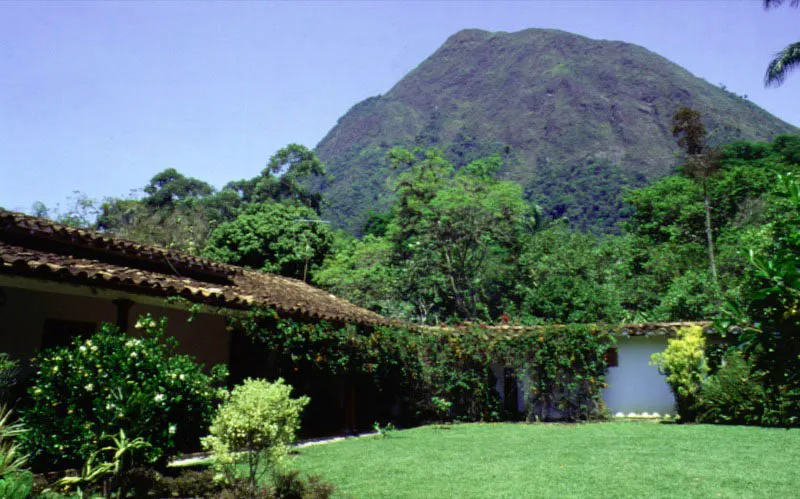 La Loma, alrededores de Santa Fe de Antioquia.
Se ilustran en estas y las siguientes páginas dos casas de la misma región e idéntico nombre. ¿Es la casa que se incrusta en el paisaje, o éste el que la invade? La casa de La Loma (nombre muy frecuente en una región tan marcadamente montañosa) data en sus tramos originales del comienzo del siglo XVIII. La exquisita integración de tejados, corredores y muros circundantes con el espacio natural en torno a éstos, es el resultado de una profunda comprensión de lo esencial del paisaje y de un prolongado y afectuoso cuidado de las formas construidas y la vegetación.
La relación expresada en estas imágenes es la de la casa y el lugar, pero también, y quizá la más importante, la del hombre y el campo.
