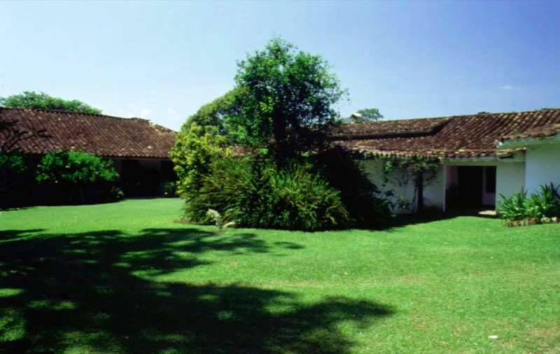 La Loma, alrededores de Santa Fe de Antioquia.
Se ilustran en estas y las siguientes páginas dos casas de la misma región e idéntico nombre. ¿Es la casa que se incrusta en el paisaje, o éste el que la invade? La casa de La Loma (nombre muy frecuente en una región tan marcadamente montañosa) data en sus tramos originales del comienzo del siglo XVIII. La exquisita integración de tejados, corredores y muros circundantes con el espacio natural en torno a éstos, es el resultado de una profunda comprensión de lo esencial del paisaje y de un prolongado y afectuoso cuidado de las formas construidas y la vegetación.
La relación expresada en estas imágenes es la de la casa y el lugar, pero también, y quizá la más importante, la del hombre y el campo.
