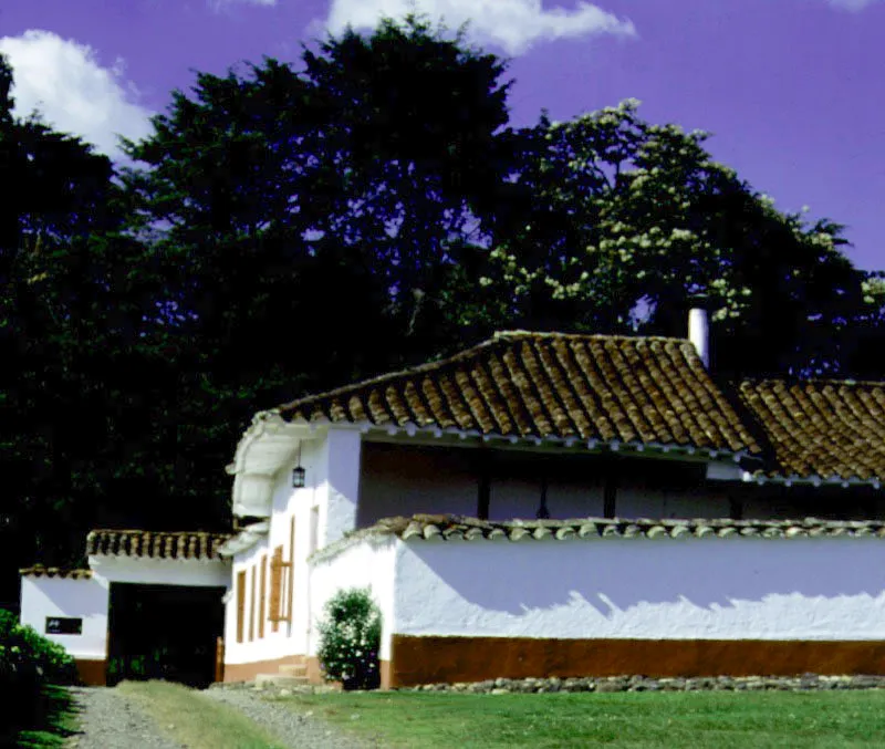Rastrojogrande, La Virginia, Antioquia. Construida, al menos en parte, durante el siglo XVIII, la casa tuvo durante el XIX las transformaciones usuales señaladas
a propósito de
otras arquitecturas rurales en la región antioqueña, sumadas a no pocas ampliaciones de vanos y otras modernizaciones más o menos inevitables.
El frente longitudinal de la casa conserva una placentera rusticidad que, si no es original, al menos resulta muy antigua. Nótense los largos aleros y, en primer plano, un apeadero para descender del caballo o el coche. Ocasionalmente es posible observar uno de éstos en algunos cortijos andaluces donde se crían o se mantienen caballos.