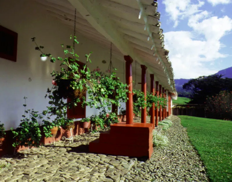 Rastrojogrande, La Virginia, Antioquia. Construida, al menos en parte, durante el siglo XVIII, la casa tuvo durante el XIX las transformaciones usuales señaladas
a propósito de
otras arquitecturas rurales en la región antioqueña, sumadas a no pocas ampliaciones de vanos y otras modernizaciones más o menos inevitables.
El frente longitudinal de la casa conserva una placentera rusticidad que, si no es original, al menos resulta muy antigua. Nótense los largos aleros y, en primer plano, un apeadero para descender del caballo o el coche. Ocasionalmente es posible observar uno de éstos en algunos cortijos andaluces donde se crían o se mantienen caballos.
