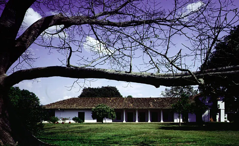 Cartama, alrededores de Guamo, Tolima.
Se le podría asignar también un carácter mixto, o transicional, análogo al de las haciendas vallecaucanas de comienzos del siglo XIX, sin la originalidad nueva
de los ejemplos de época puramente republicana.
El aspecto actual de la casa de Cartama se conformó a raíz de recientes reformas y una considerable modernización de lo que fue un caserón levantado a fines del siglo XIX sobre lo que debió ser una modesta casa del siglo XVIII, sobre el terreno de una hacienda fundada a comienzos del siglo XVII. Ha persistido a través de las épocas
la organización en planta de la casa en un tramo longitudinal, aunque las galerías perimetrales completas en postes y dinteles de madera que tenía en la década de los cincuenta ya no existen, siendo reemplazadas por columnatas “modernas”. El volumen realzado en uno de los extremos, a la manera de las casas caucanas, existió desde época indeterminada.