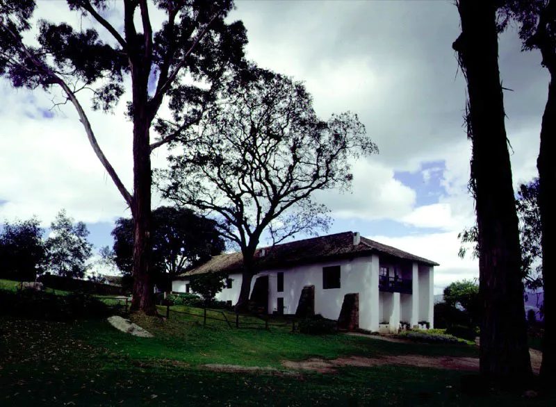 El Noviciado, Cota, Cundinamarca. Galería del piso bajo que muestra las columnas de piedra procedentes de la casa cural de Chía que reemplazaron recientemente los postes de madera más antiguos y el piso de ladrillo que sustituyó al de adobes.