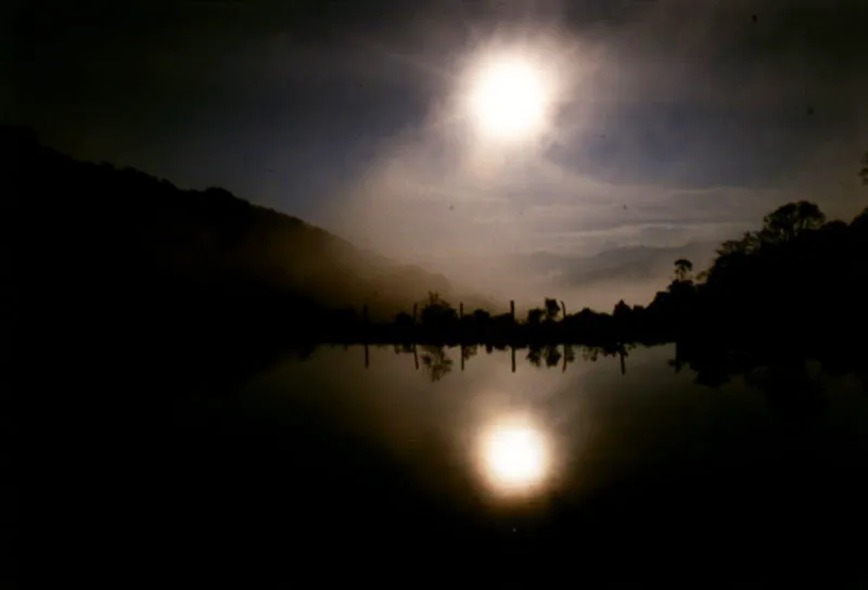 La penumbra del anochecer iluminada por los restos de luz tras la barrera de montañas. Reflejos de bosque y luna en los Laguitos de La Floresta.