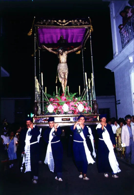 Paso del Santo Cristo. Por ser Viernes Santo los cargueros llevan el pao blanco cruzado sobre el pecho y sobre el pao la cruz, con una pequea corona de violetas frescas encima. 