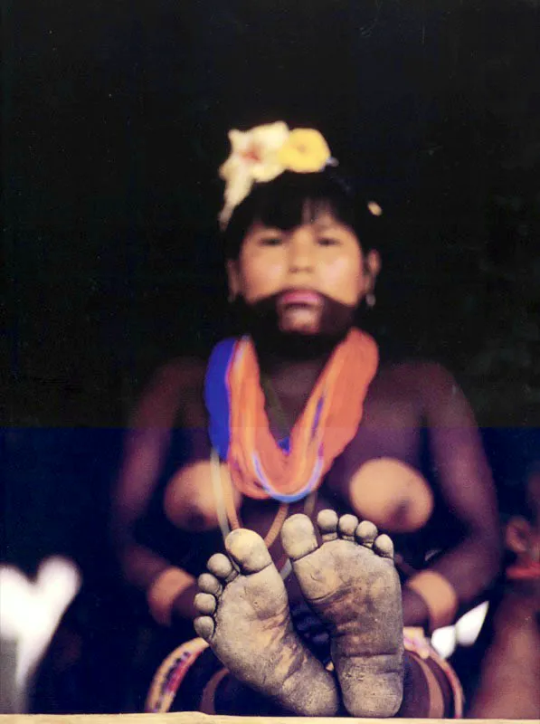Sentada sobre
el suelo elevado de su vivienda de palafito,
una indígena Emberá del Chocó luce atuendos de flores,
collares y pictografía corporal, aun en la rutina descalza de su cotidianidad.
Aldo Brando