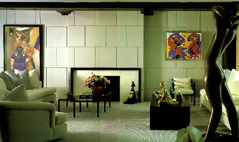 La sala, con sus colores apagados y las líneas limpias del mobiliario, constituye un fondo neutro para exhibir la notable colección de arte de los clientes. A la izquierda de la chimenea de mármol y granito puede verse un cuadro de Fernando Botero, y a la derecha una obra de Karl Appel. La figura en bronce del primer plano es de Rovus.