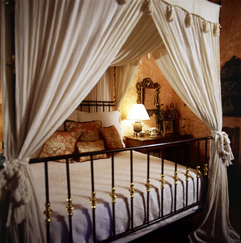 Dormitorio de casa en Antigua, con cama contemporánea de hierro forjado y baldaquín.