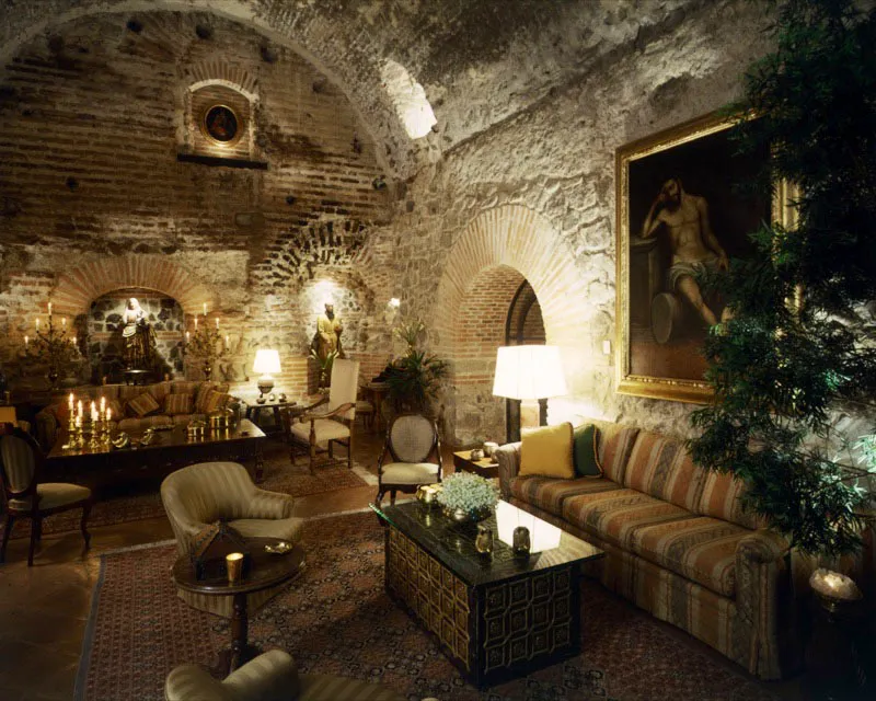 Salón principal de casa en Antigua, incorporado al espacio original abovedado, con paredes en ladrillo y piedra a la vista, decorado con muebles contemporáneos y pinturas y tallas coloniales.