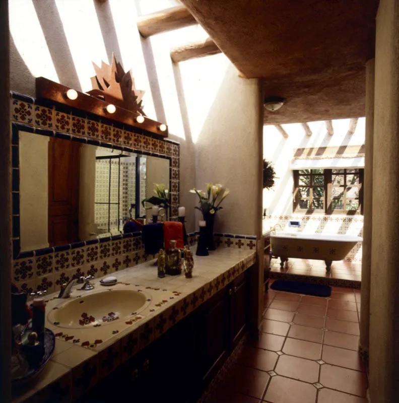 Detalle del lavabo de un baño de una casa en el lago de Amatitlán, decorado con azulejos, y un tragaluz en el que se observan rústicas vigas de madera. El piso, de baldosa de barro, está incrustado de azulejos.