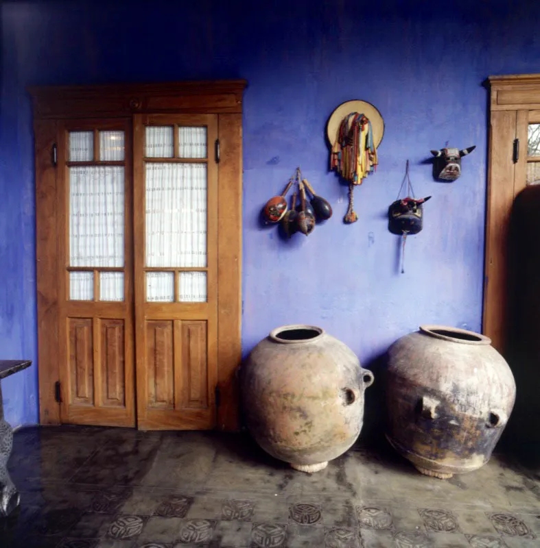 Detalle del corredor de una casa antigüeña actual adornado con máscaras indígenas, maracas y grandes recipientes de barro.