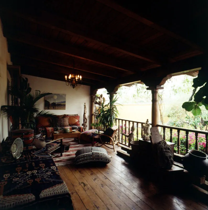 Galería abierta frente al patio de la pila, en la segunda planta de una casa antigüeña, con suelo de duela de madera y una combinación de elementos y textiles guatemaltecos e indonesios.