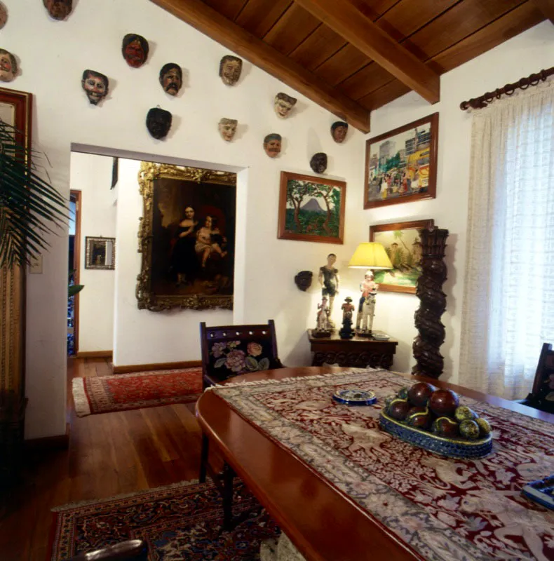 Comedor con máscaras indígenas y pinturas de Miguel García Luque, en ciudad de Guatemala. Muebles variados, columna salomónica, esculturas coloniales y cuadros antiguos y modernos.