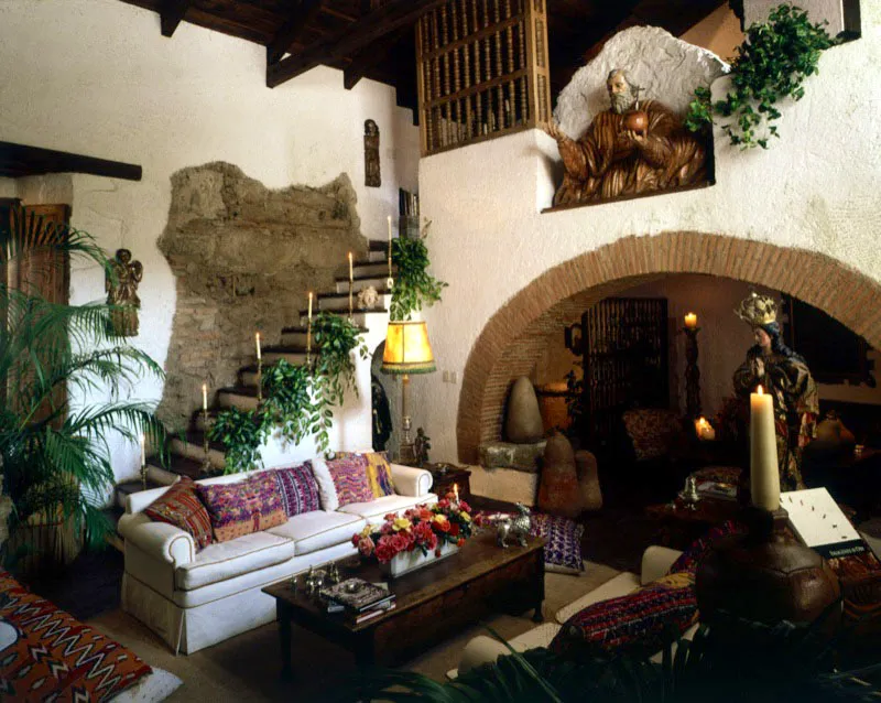 Una escultura de Dios Padre domina el ambiente de esta sala en una casa restaurada de Antigua, cuyo arco rebajado con los ladrillos vistos integra los dos espacios, decorados con mobiliario rústico y moderno, tallas coloniales y piezas de plata.