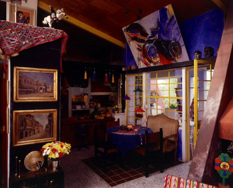 Comedor-cocina pintoresco y ecléctico, en una pequeña casa contemporánea de ciudad de Guatemala. Encima del comedor gran cuadro del pintor José Antonio Fernández.